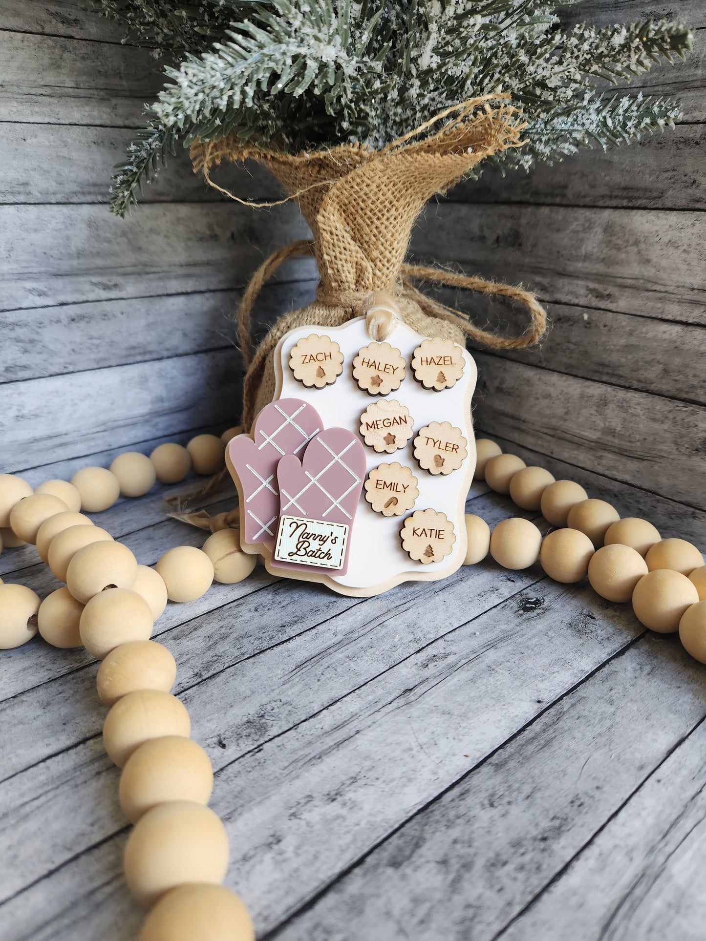 Decorative wreath with wooden beads, burlap ribbon, and festive elements on a wooden surface.