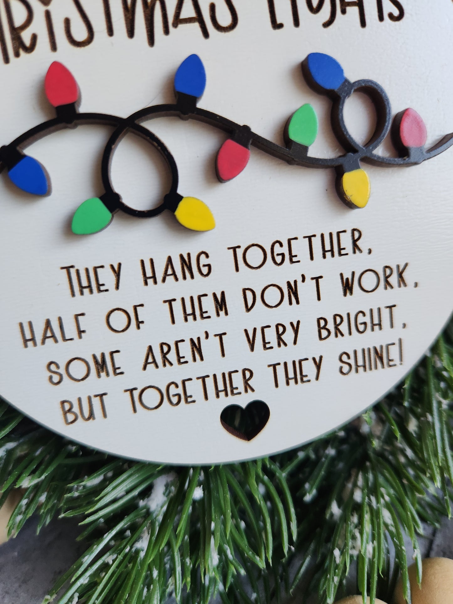 Decorative Christmas ornament with colorful lights and engraved text on a white background.