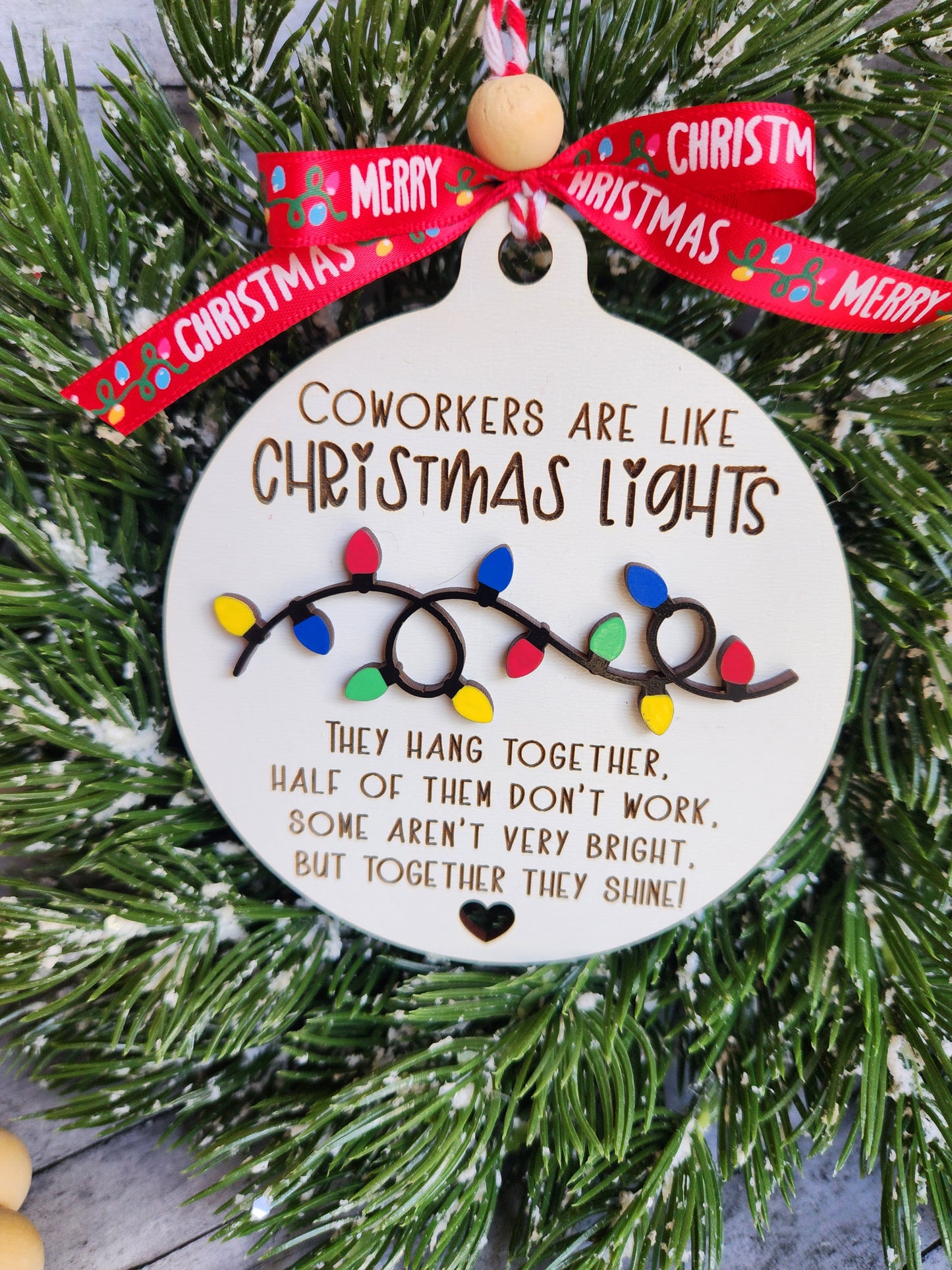 Decorative Christmas ornament with text and lights on a green wreath.
