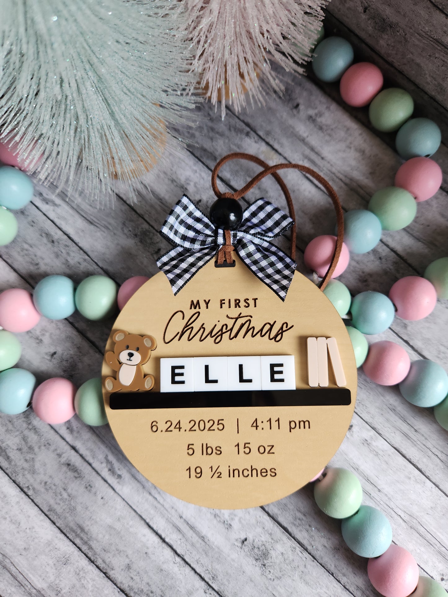 Wooden ornament with baby's first Christmas details on a colorful bead garland.