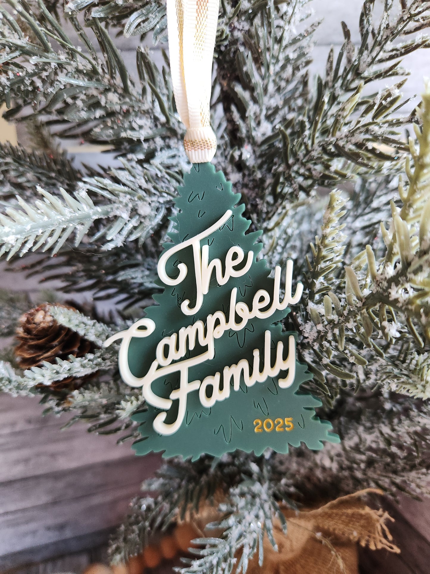 Personalized Christmas ornament with 'The Campbell Family' text on a decorated tree.