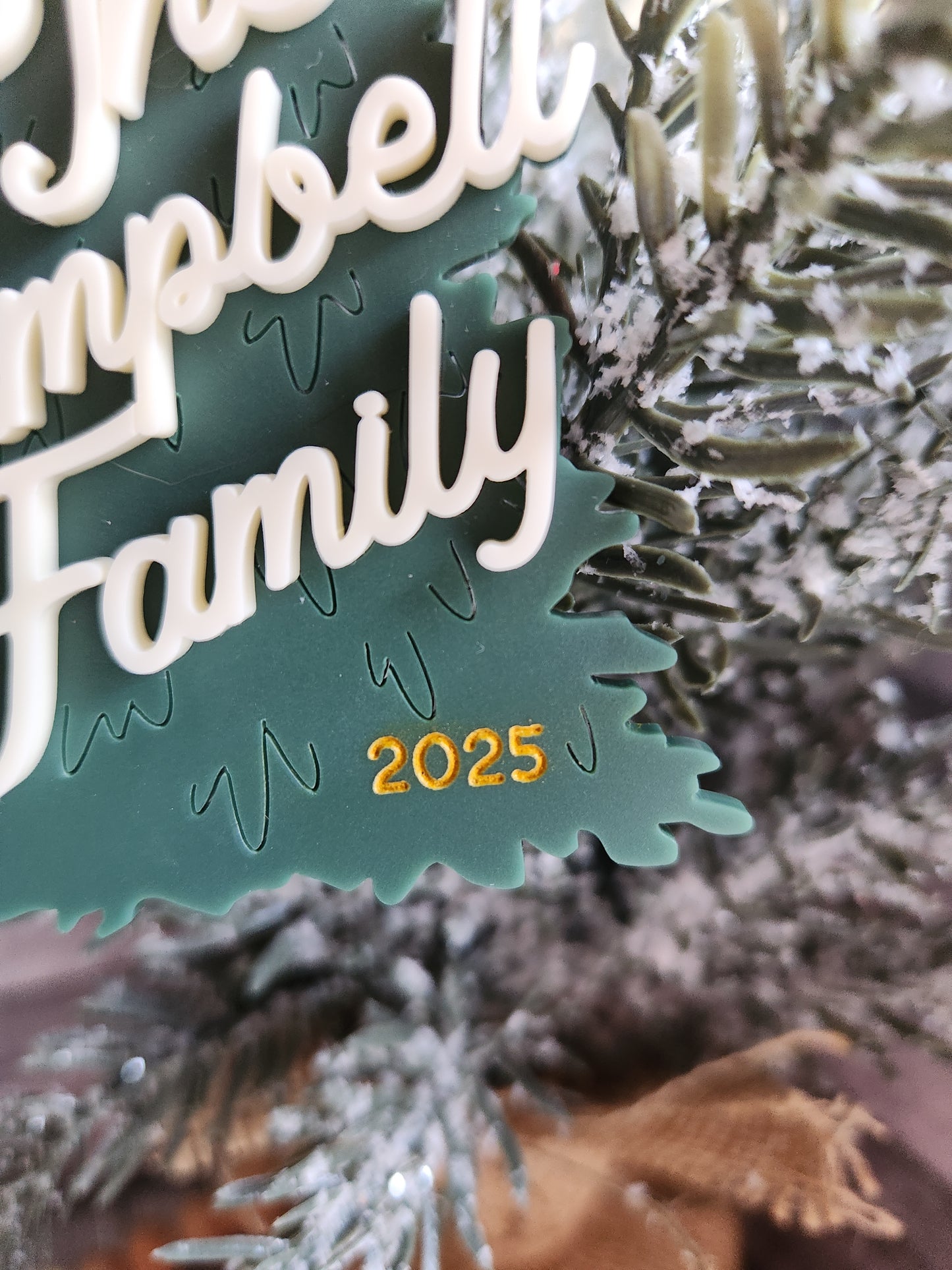 Decorative ornament with 'Happy Family 2025' text on a Christmas tree.