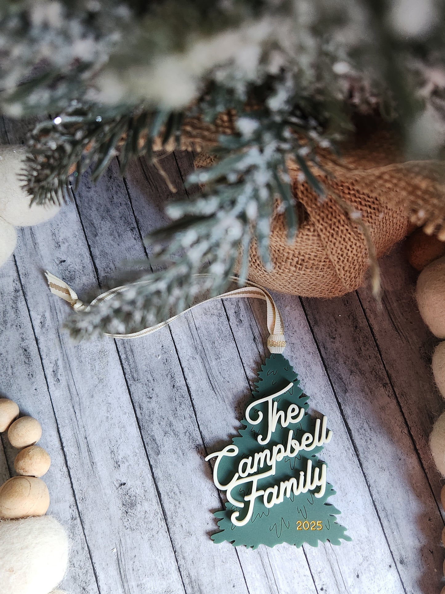 Decorative sign with 'The Campbell Family' on a wooden surface with Christmas decorations.