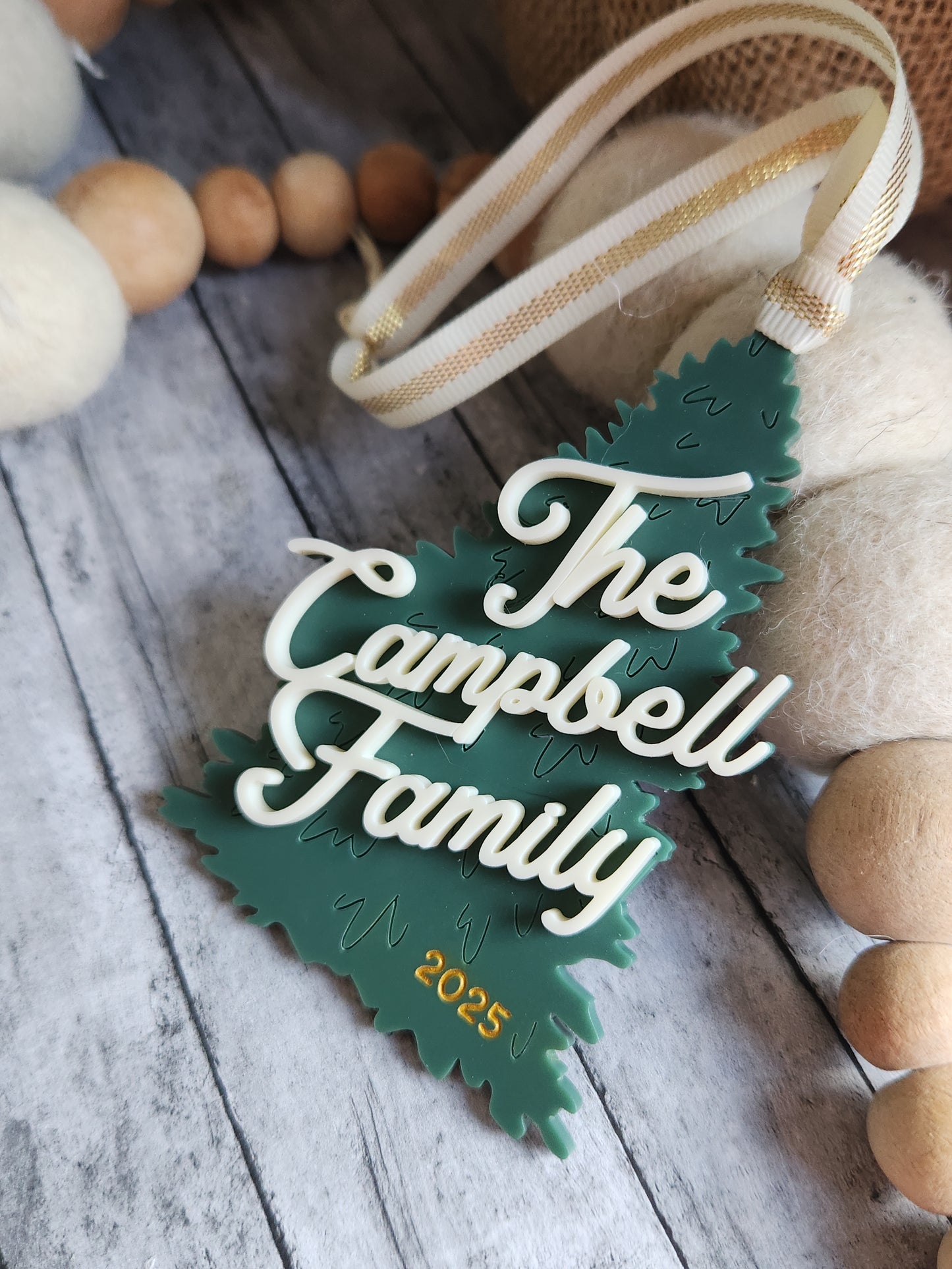Decorative leaf-shaped ornament with 'The Campbell Family' and year on a wooden surface.