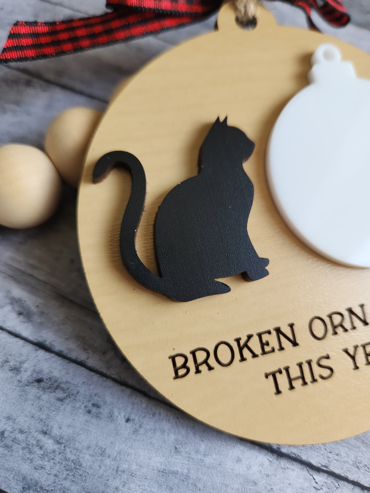 Wooden ornament with black cat silhouette and text on a gray surface