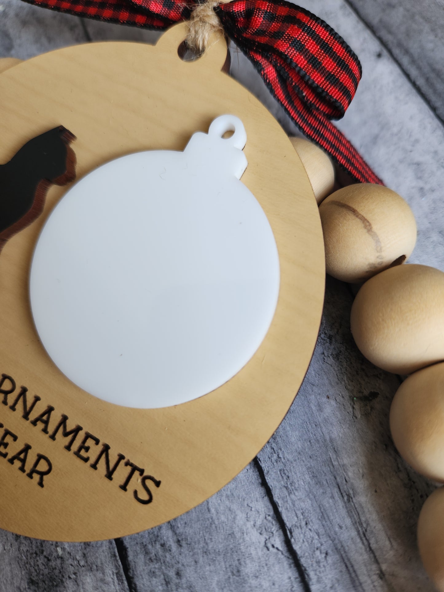 Round wooden ornament with a white circle for customization, featuring a black cat design, on a rustic wooden surface.