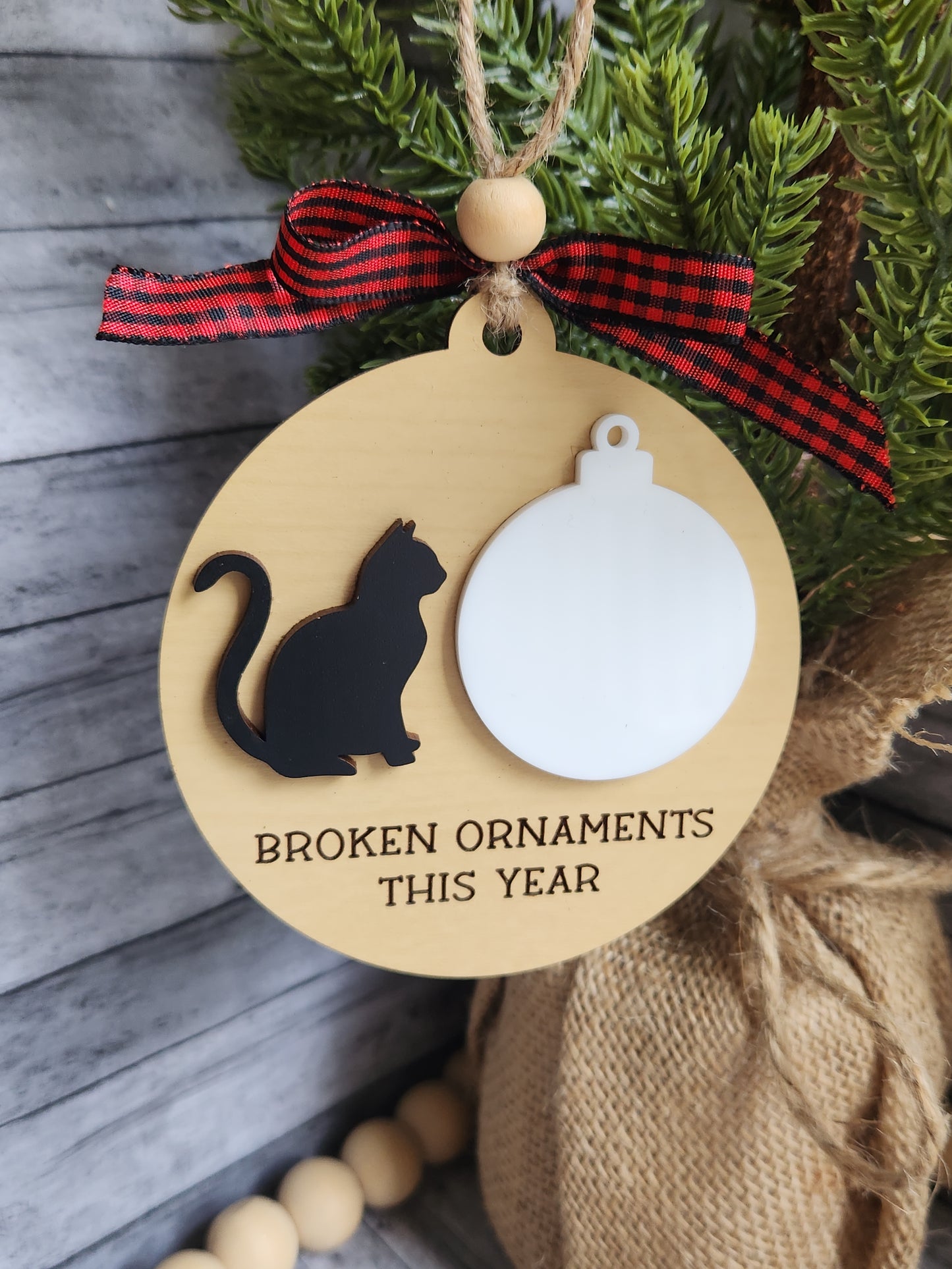 Decorative ornament with a cat silhouette and text on a wooden background