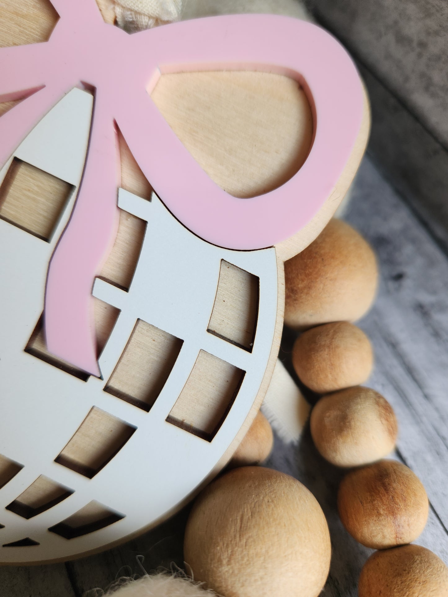 Decorative items including a pink ribbon and wooden beads on a textured surface