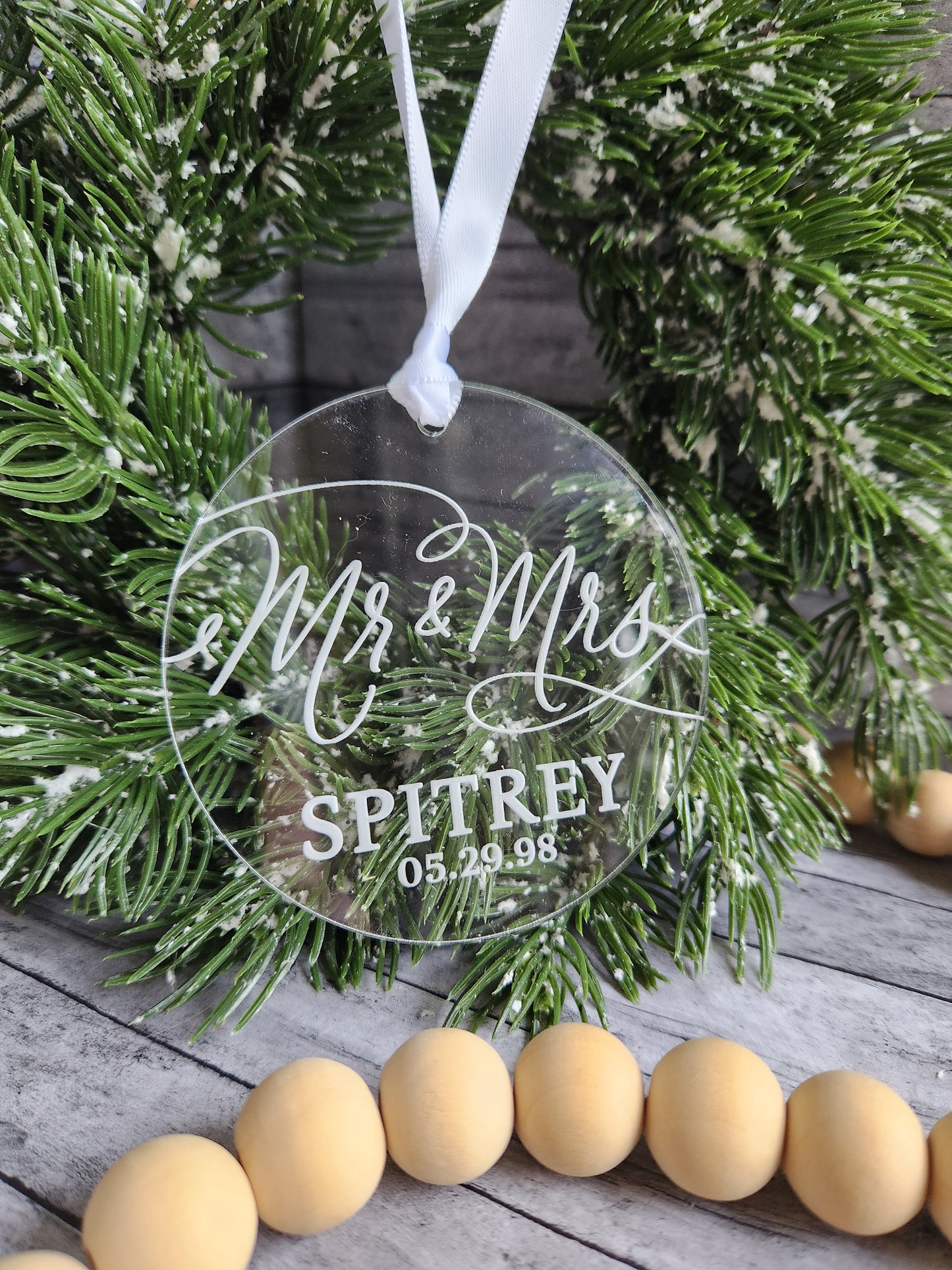 Personalized Christmas ornament with 'Mr & Mrs' and 'last name text, placed on a festive background.