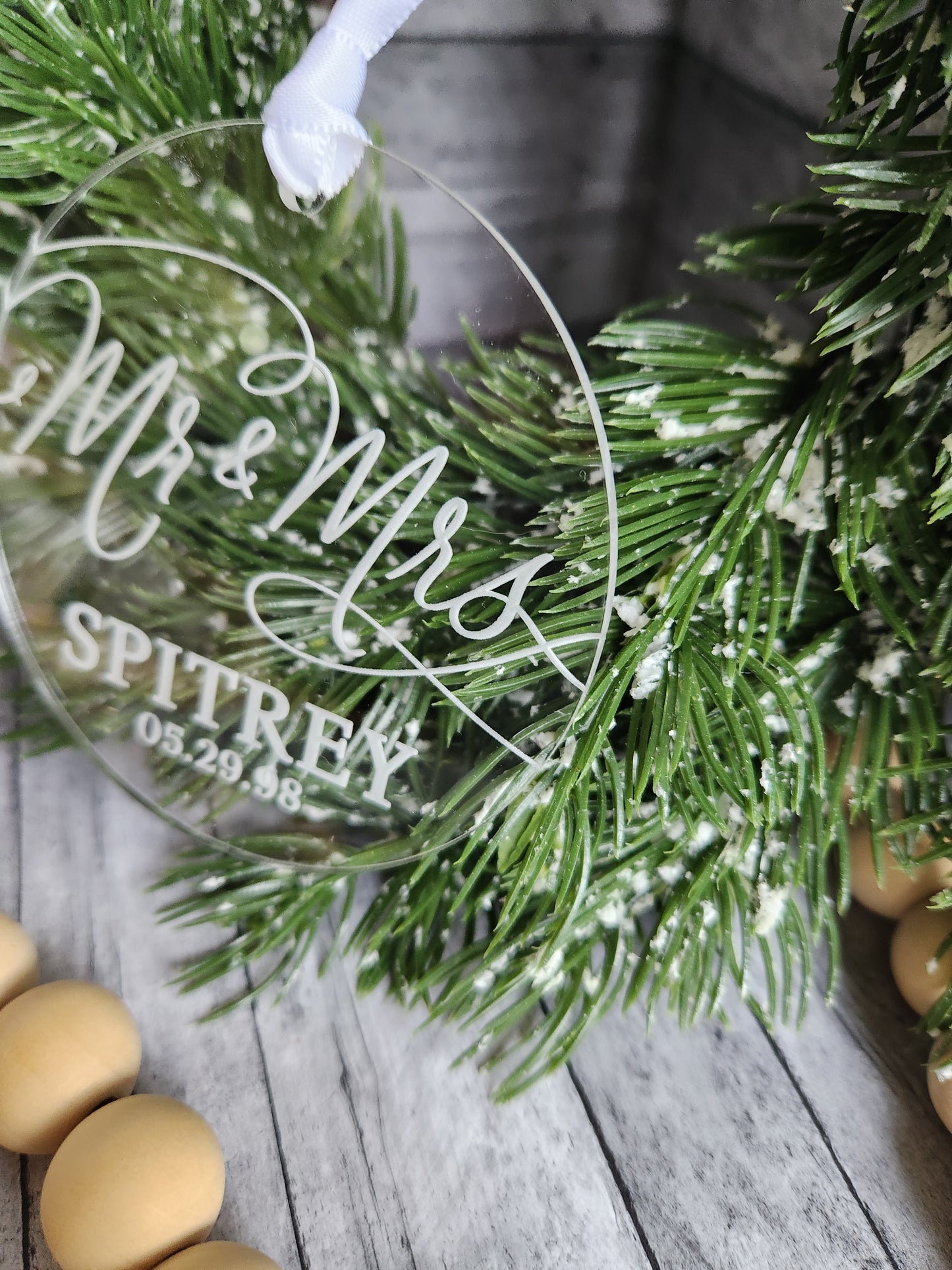 Decorative glass plate with engraved text on a Christmas wreath and wooden surface.
