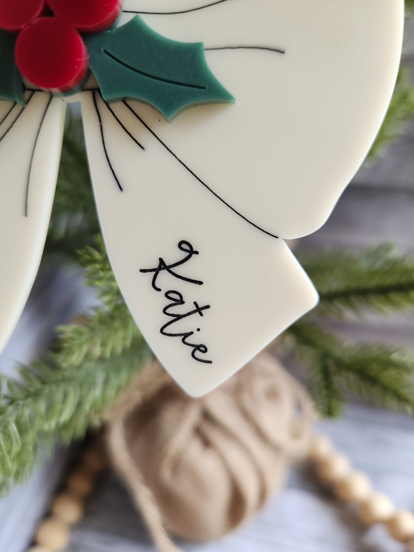 Decorative bow with 'Katie' written on it, Christmas tree and decorations in the background
