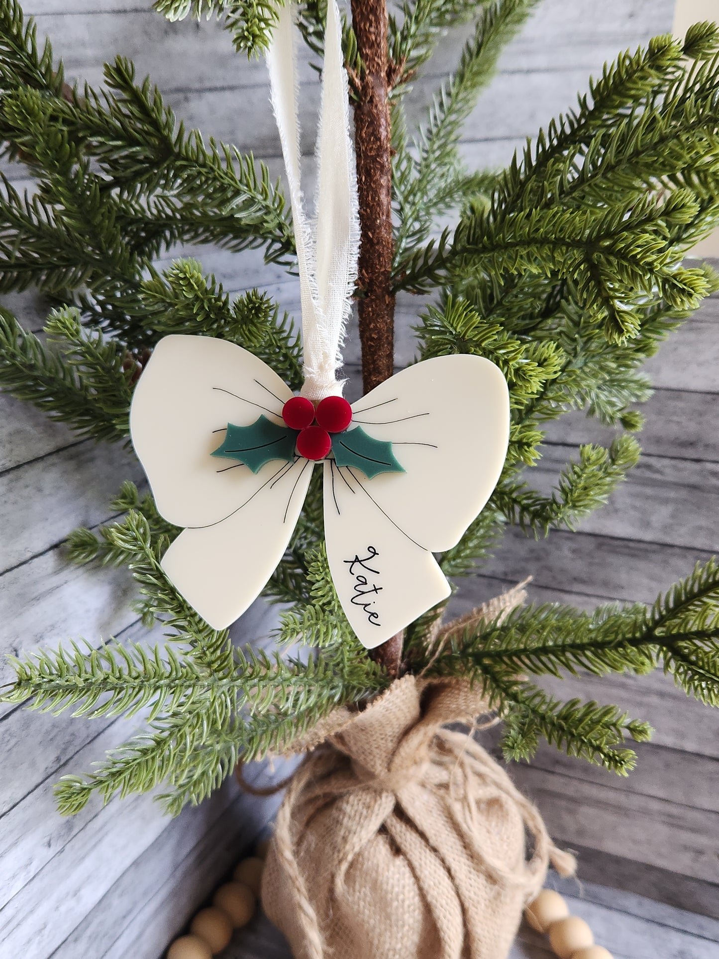 Decorative butterfly ornament with 'Katie' on a branch with greenery