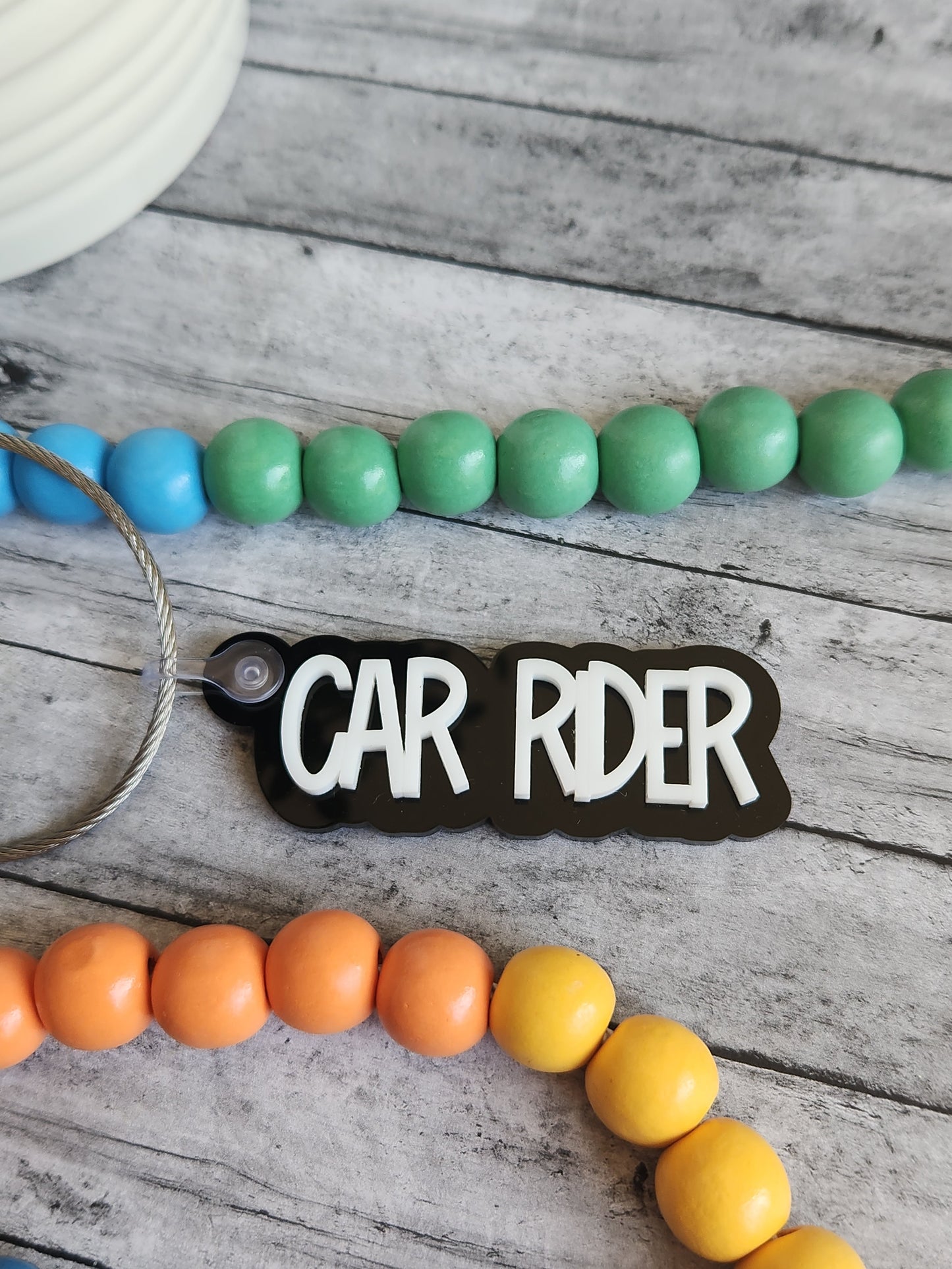 Colorful beaded keychains with 'CAR RDER' tag on a wooden surface