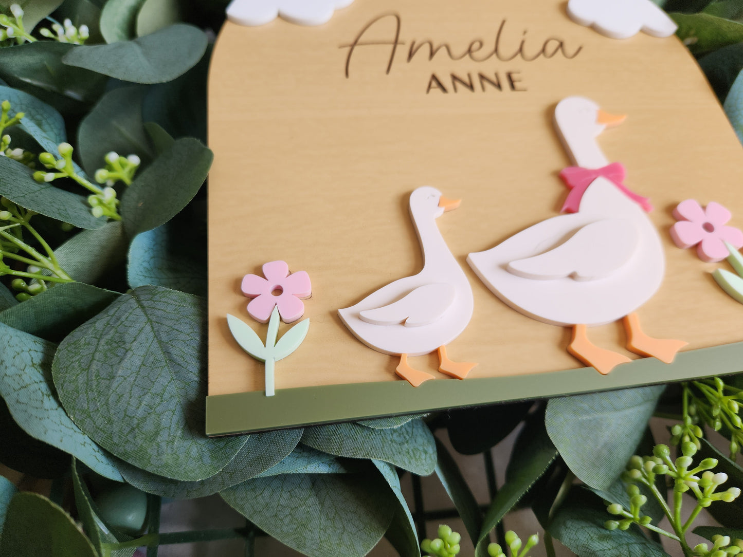 Card with cut-out flamingo design and 'Anne' text, surrounded by green leaves.