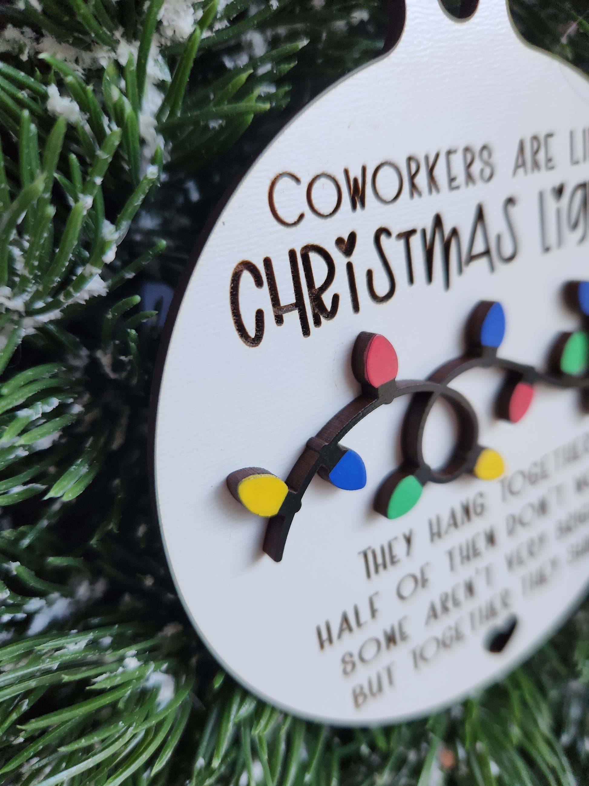 Decorative ornament with Christmas lights and text on a green pine branch background
