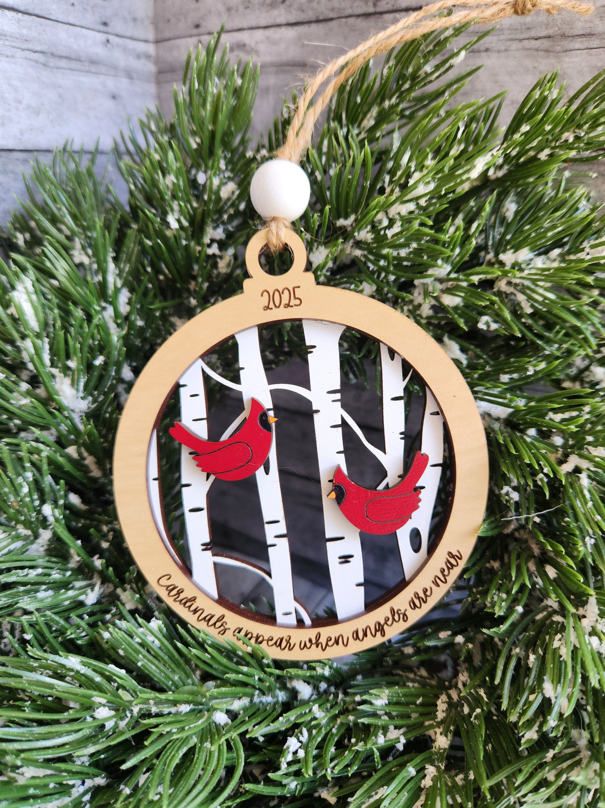Decorative Christmas ornament with red birds on a black and white pattern, hanging on a green wreath.