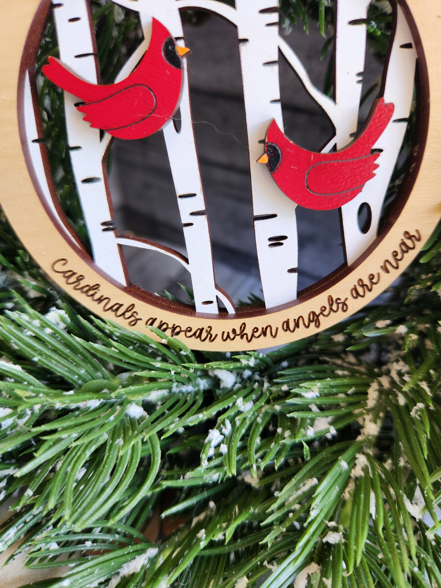 Decorative wall hanging with red birds and engraved text on a green wreath background