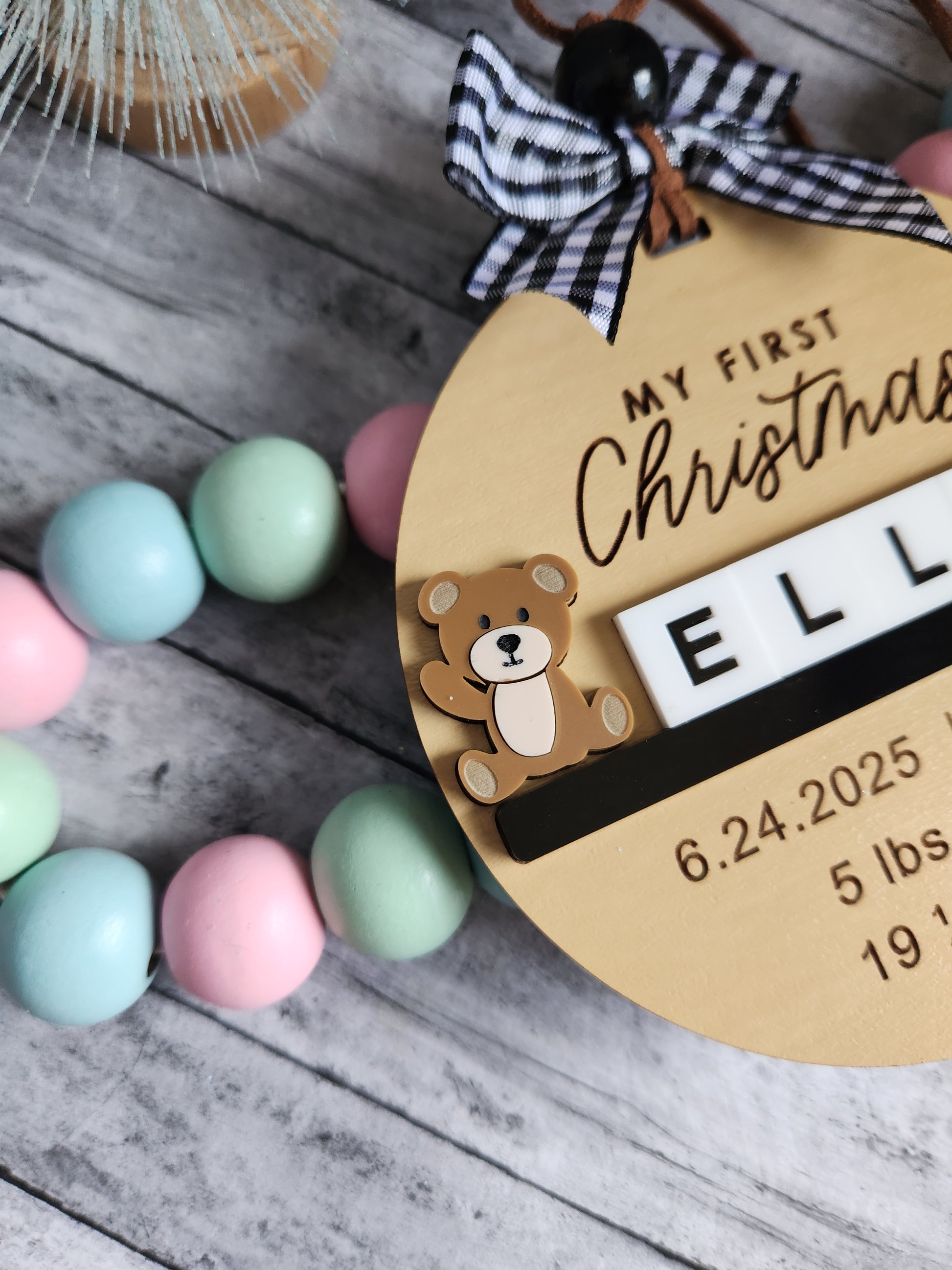 Personalized baby item with teddy bear design and text on a wooden surface