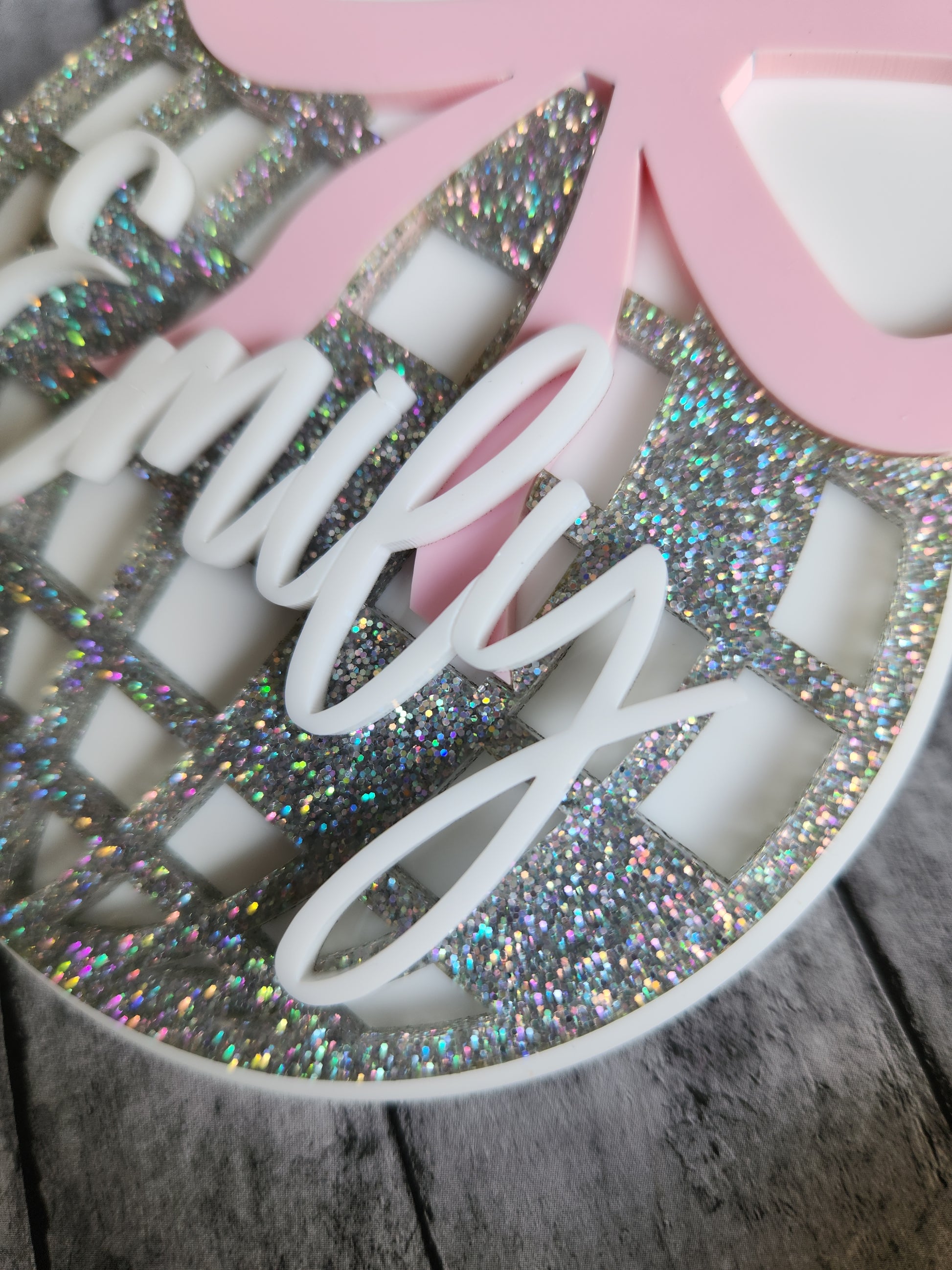 Decorative item with pink bow and glittery surface on a wooden background