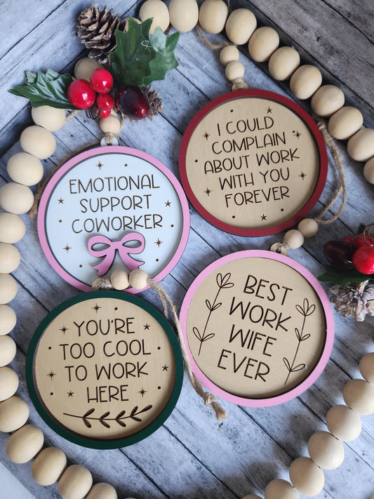 Decorative wooden ornaments with humorous sayings on a wooden surface with beads and small decorations.
