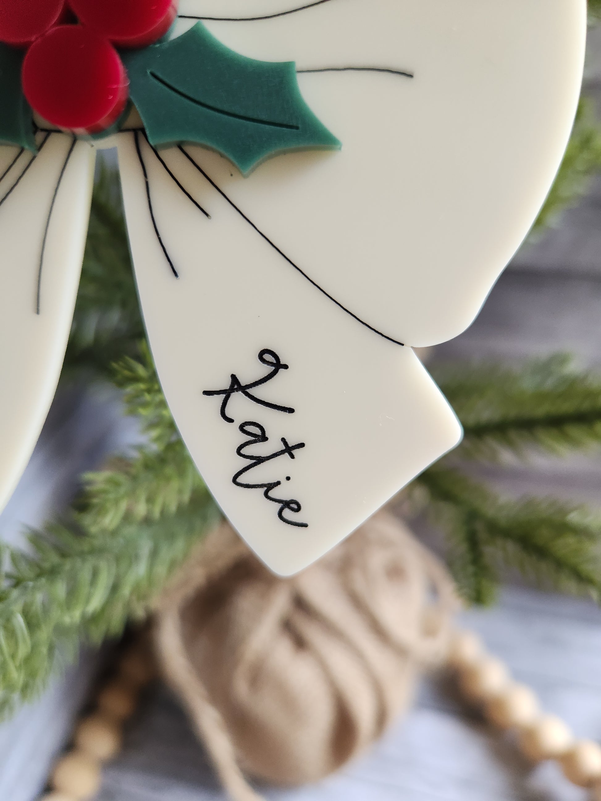 Decorative bow with 'Katie' written on it, Christmas tree and decorations in the background