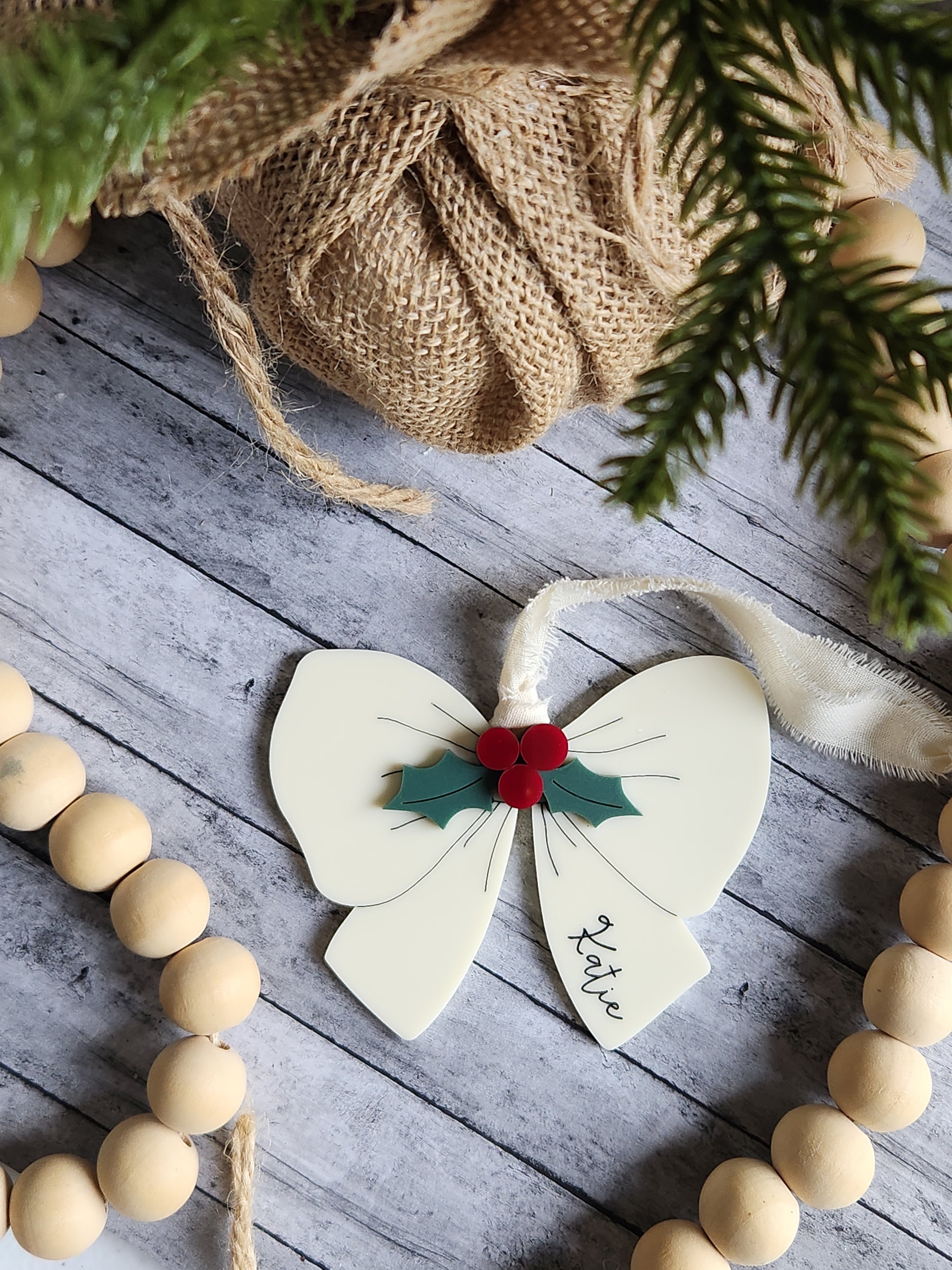 Decorative butterfly ornament with red center and green leaf on a wooden surface with Christmas decorations.