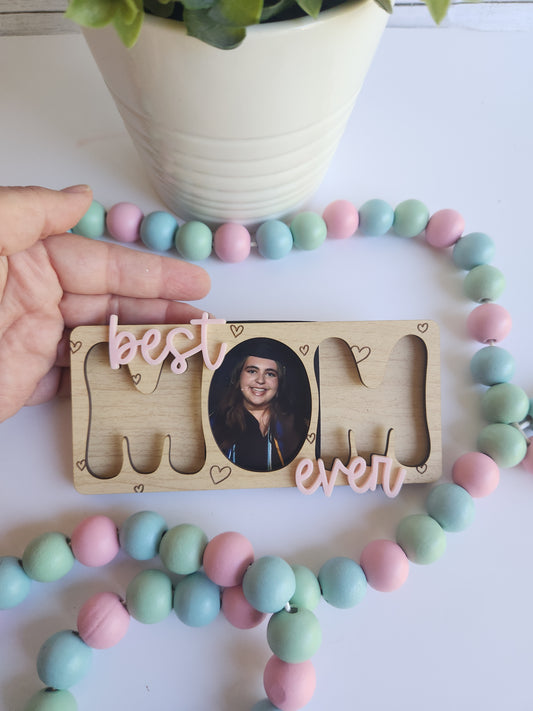 Wooden Mom photo frame magnet with “Best Mom Ever” design, picture magnet gift for mom holding up to 3 photos, displayed with pastel bead decor and greenery.