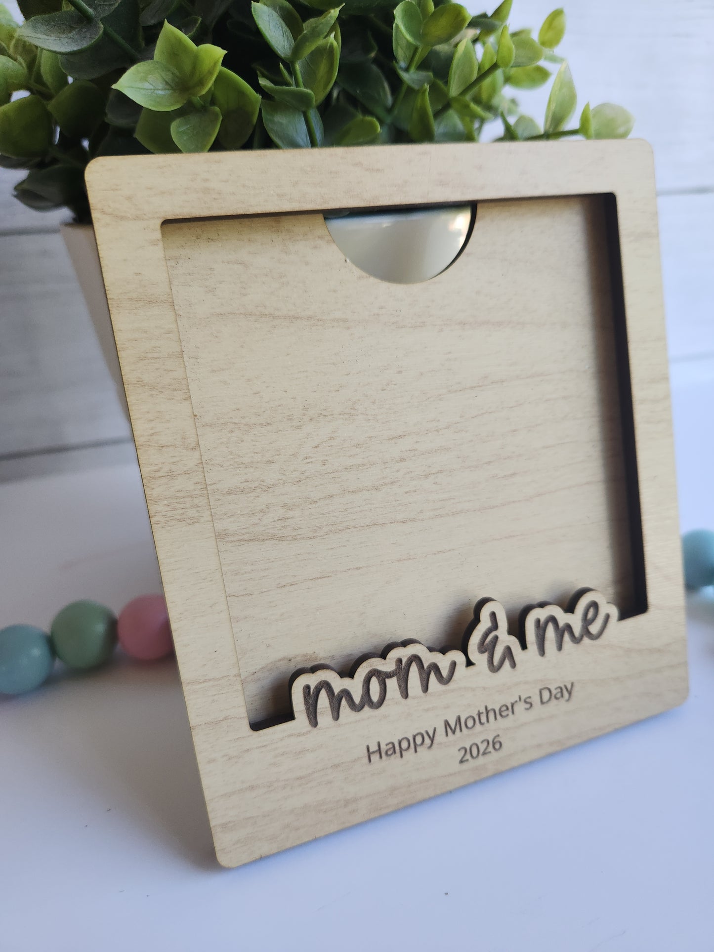 Personalized wooden Polaroid photo frame engraved with “Mom & Me” and Happy Mother’s Day message, custom gift for mom displayed with pastel decor and greenery.