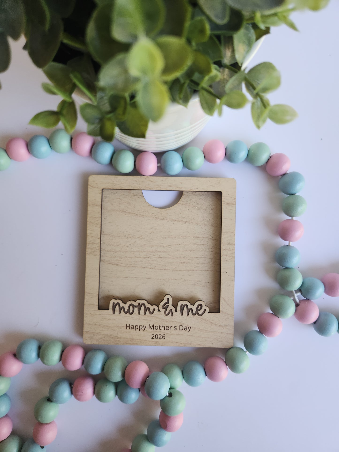 Pastel-colored beaded necklace with a wooden frame on a white background