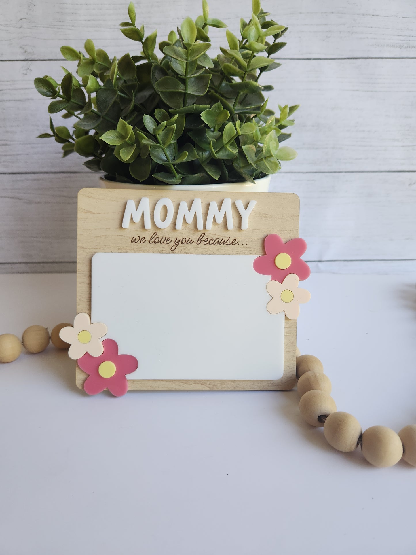 Wooden photo frame with 'Mommy' and decorative flowers on a light wooden surface.